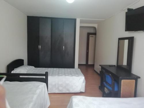 a hotel room with two beds and a television at Hotel Oicatá in Duitama