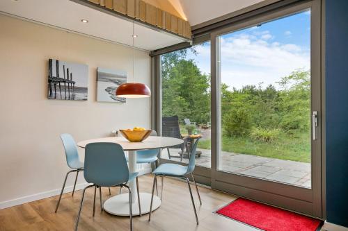 ein Esszimmer mit einem Tisch und Stühlen sowie einem großen Fenster in der Unterkunft Wad Else in Lauwersoog