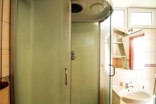 a green shower door in a bathroom with a sink at Vienas po kitu in Šventoji