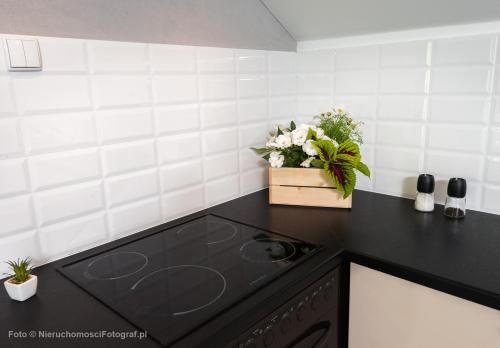 a kitchen with a black counter top with flowers on it at Orbisa Pokoje i Apartamenty in Łeba