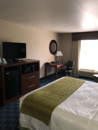 a hotel room with a bed and a flat screen tv at Countryview Inn & Suites in Robinson