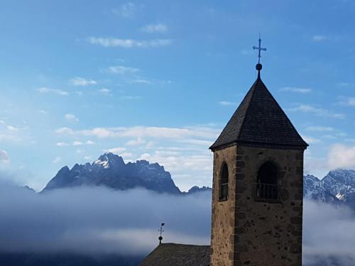 a tower with a cross on top of a building with mountains at La Suite in Candide