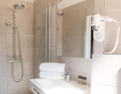 a bathroom with a shower and a sink and a mirror at Hotel La Voile in Bormes-les-Mimosas