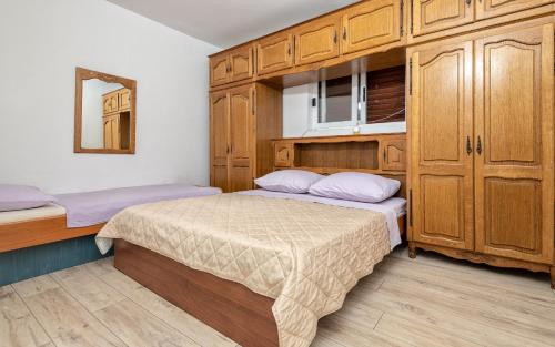 a small bedroom with two beds and wooden cabinets at Tea Two Apartman in Neum