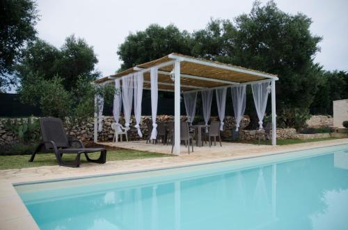 a pavilion with a table and chairs next to a pool at Trullo Grazioso Luxury in Ceglie Messapica