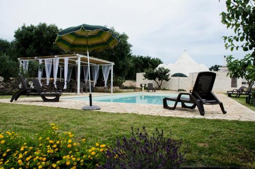 a pool with two lawn chairs and an umbrella at Trullo Grazioso Luxury in Ceglie Messapica