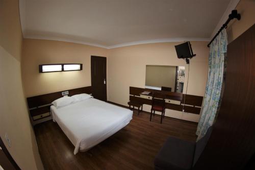 ポルティマンにあるResidencial Solのベッドとデスクが備わるホテルルームです。
