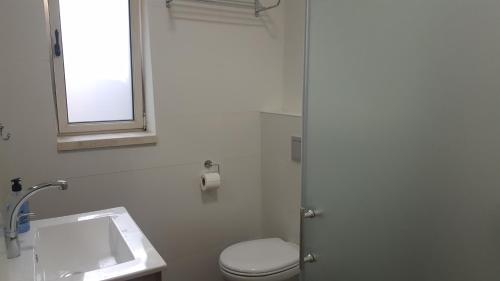 a bathroom with a toilet and a sink and a window at Engel apartments -אירוח למטיילים בגליל עליון in Tsiv'on