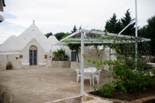 a patio with a pergola and tables and chairs at Trullo Grazioso Luxury in Ceglie Messapica