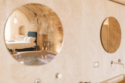 a bathroom with a tub with a bed in the background at Palazzo Del Duca Hotel & Restaurant in Matera