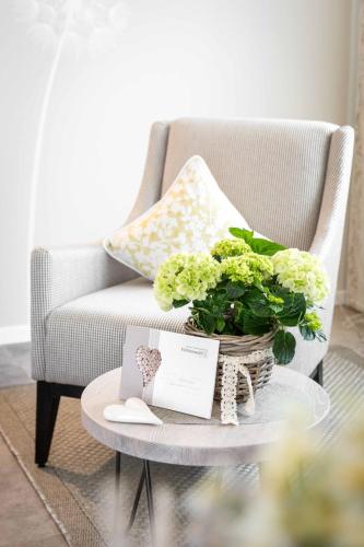 a living room with a chair and a table with a plant at Fichtenwald-Ihr Boutique I Glück`s Hotel in Bad Füssing