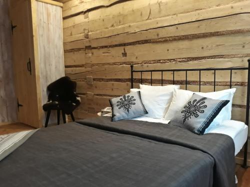 a bedroom with a bed with pillows and a wooden wall at Jak Sobie Pościelisz Tak Się Wyśpisz in Zakopane