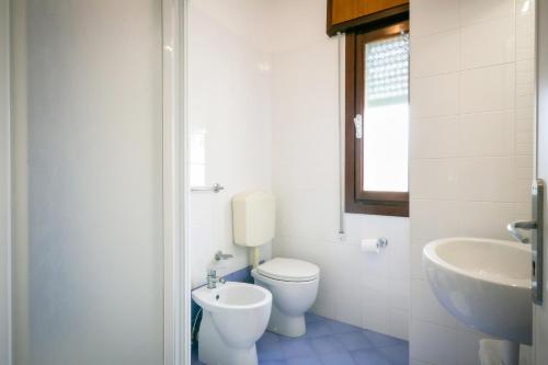 a white bathroom with a toilet and a sink at Hotel Verona in Caorle