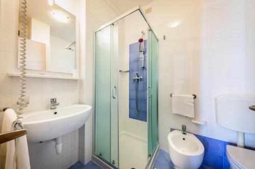 La salle de bains est pourvue d'un lavabo et d'une douche en verre. dans l'établissement Hotel Verona, à Caorle