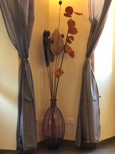 a vase with flowers in it next to two curtains at ABCdecor Italia in Imperia