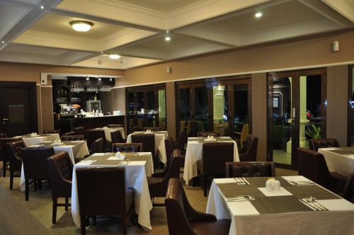 restauracja z białymi stołami i krzesłami oraz bar w obiekcie Casa de Wanea Hotel w mieście Manado