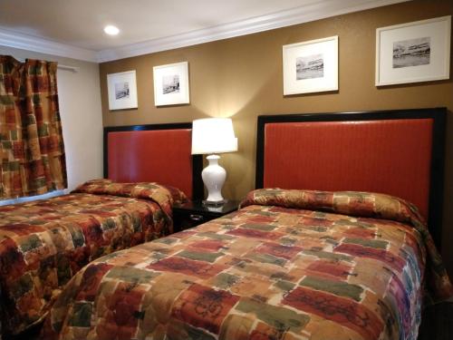 a hotel room with two beds and a lamp at Bartlett Motel in Lomita