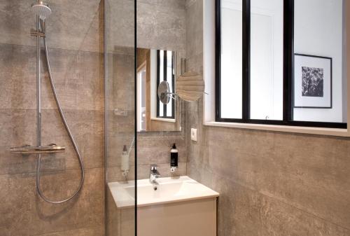 a bathroom with a shower and a sink and a mirror at Appartements des Ducs in Dijon
