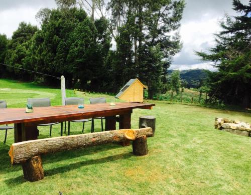 a wooden picnic table and bench in a field at HOBU MONTAÑA in La Calera