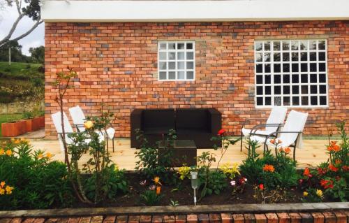 a patio with two chairs and a brick building at HOBU MONTAÑA in La Calera