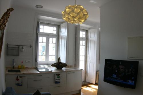 una cucina con lampadario pendente e una cucina con armadi bianchi di Casa Sesimbra a Sesimbra