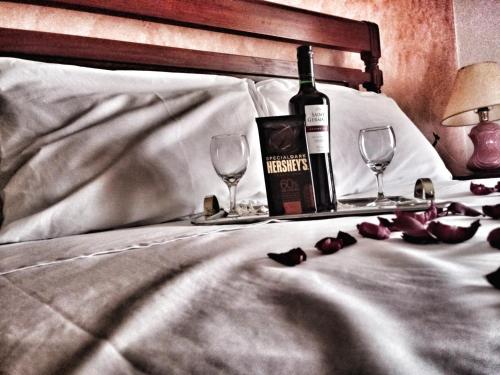 カマンドゥカイアにあるPousada das Palmeirasのベッドの上にワイン1本とグラス2杯