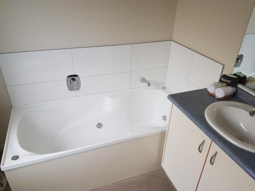 a white bathroom with a tub and a sink at Portmans Motor Lodge in Hastings