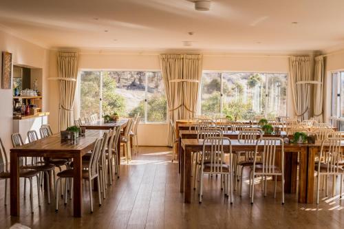 a dining room with tables and chairs and windows at Panorama Jindabyne in Jindabyne