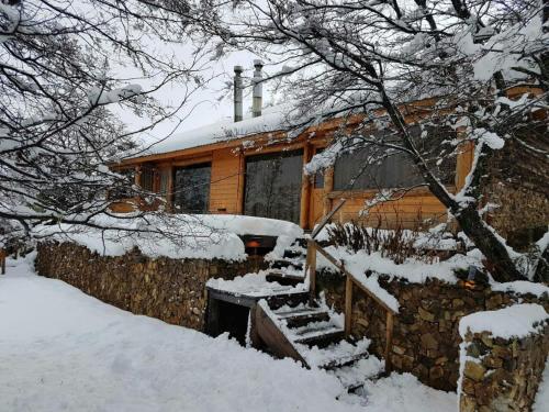 a house covered in snow with a fence and stairs at Cabañas & Lofts Las Terrazas in Villa Pehuenia