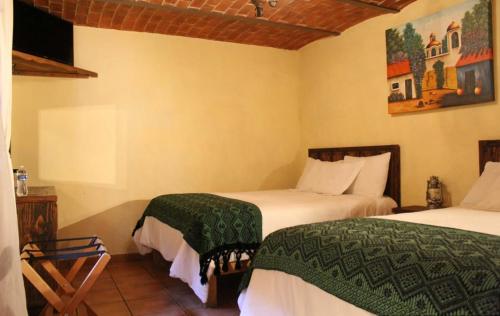 a bedroom with two beds and a painting on the wall at Meson Luna Sacra in Tapalpa