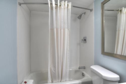 Baño blanco con cortina de ducha y aseo en Gatlinburg River Inn en Gatlinburg