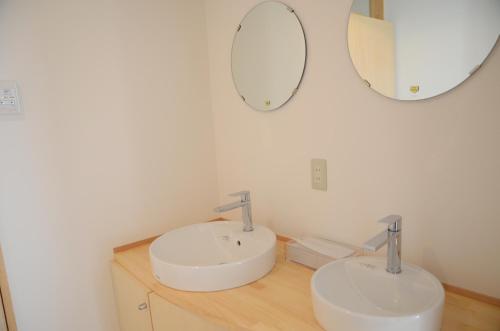 a bathroom with two sinks and two mirrors at Sai no Tsuno Guest House in Ueda