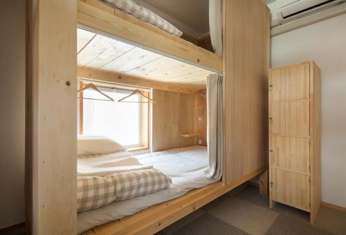 Cama en habitación de madera con ventana en Sai no Tsuno Guest House, en Ueda