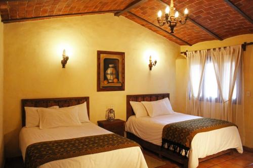 a bedroom with two beds and a chandelier at Meson Luna Sacra in Tapalpa