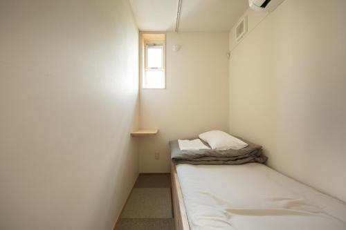 a small room with a bed and a window at Sai no Tsuno Guest House in Ueda