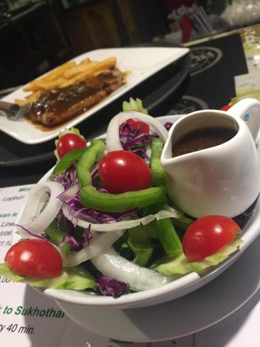 a plate with a salad and a cup of coffee at Noom Guesthouse in Lop Buri