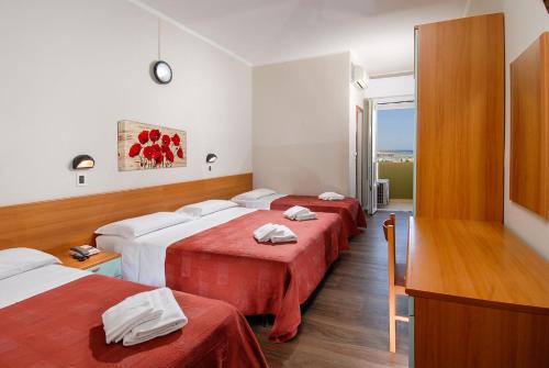 una camera d'albergo con due letti con lenzuola rosse di Hotel Colombo a Rimini