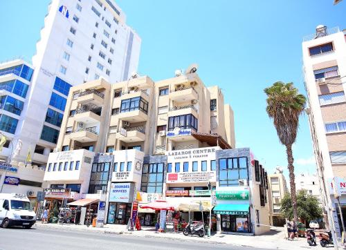 a tall building on a city street with a palm tree at Lazaros Centre Apartment in Larnaka