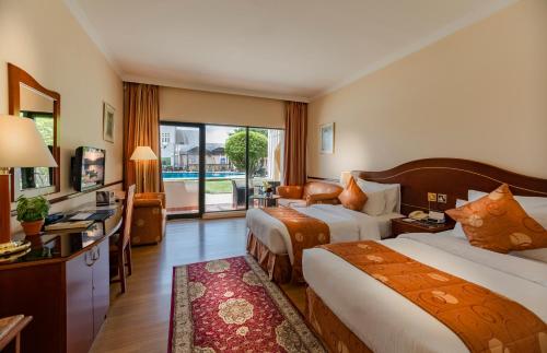 a hotel room with two beds and a television at Golden Tulip Nizwa Hotel in Nizwa
