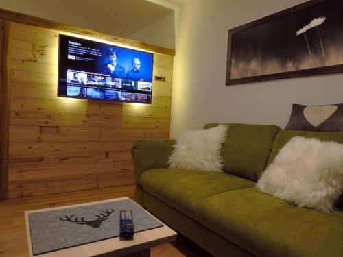 a living room with a green couch and a flat screen tv at Leos Alpenblume inklusive Sommer Bergbahnticket in Oberstdorf