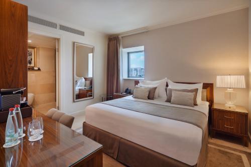 a hotel room with a large bed and a desk at Herbert Samuel Jerusalem in Jerusalem