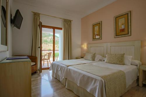 a hotel room with two beds and a balcony at Hotel Doña Lola Zahara in Zahara de los Atunes