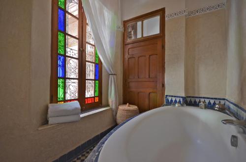 a bathroom with a tub and a stained glass window at Dar Roumana in Fès