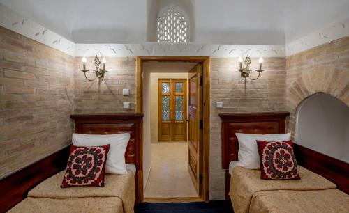 two beds in a room with a door and two pillows at Orient Star Khiva Hotel- Madrasah Muhammad Aminkhan 1855 in Khiva