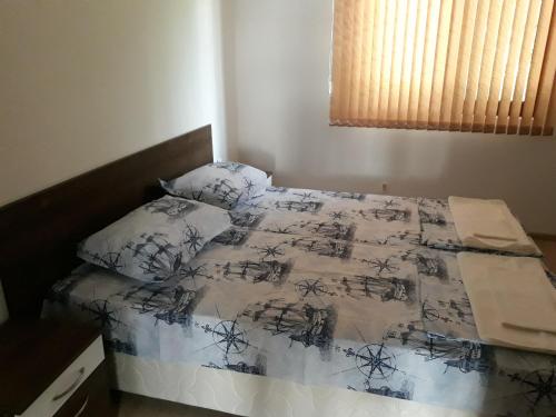1 dormitorio con 1 cama con edredón blanco y negro en Апартамент Явор en Balchik