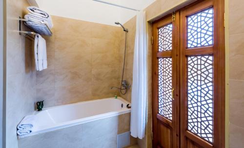 a bathroom with a bath tub and a window at Orient Star Khiva Hotel- Madrasah Muhammad Aminkhan 1855 in Khiva