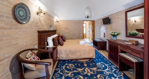 a bedroom with a bed and a vanity and a mirror at Orient Star Khiva Hotel- Madrasah Muhammad Aminkhan 1855 in Khiva