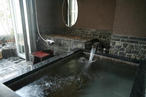 a bathroom with a tub with a water fountain at Tabinoyado Ushionoakari Geiboso in Shima
