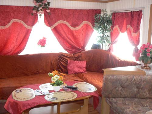 ソボトカにあるUbytovani Fanisek v mobilnim domku v ceskem rajiのリビングルーム(赤いカーテン、ソファ付)