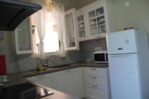 a kitchen with white cabinets and a white refrigerator at Villa Martha in Benitses